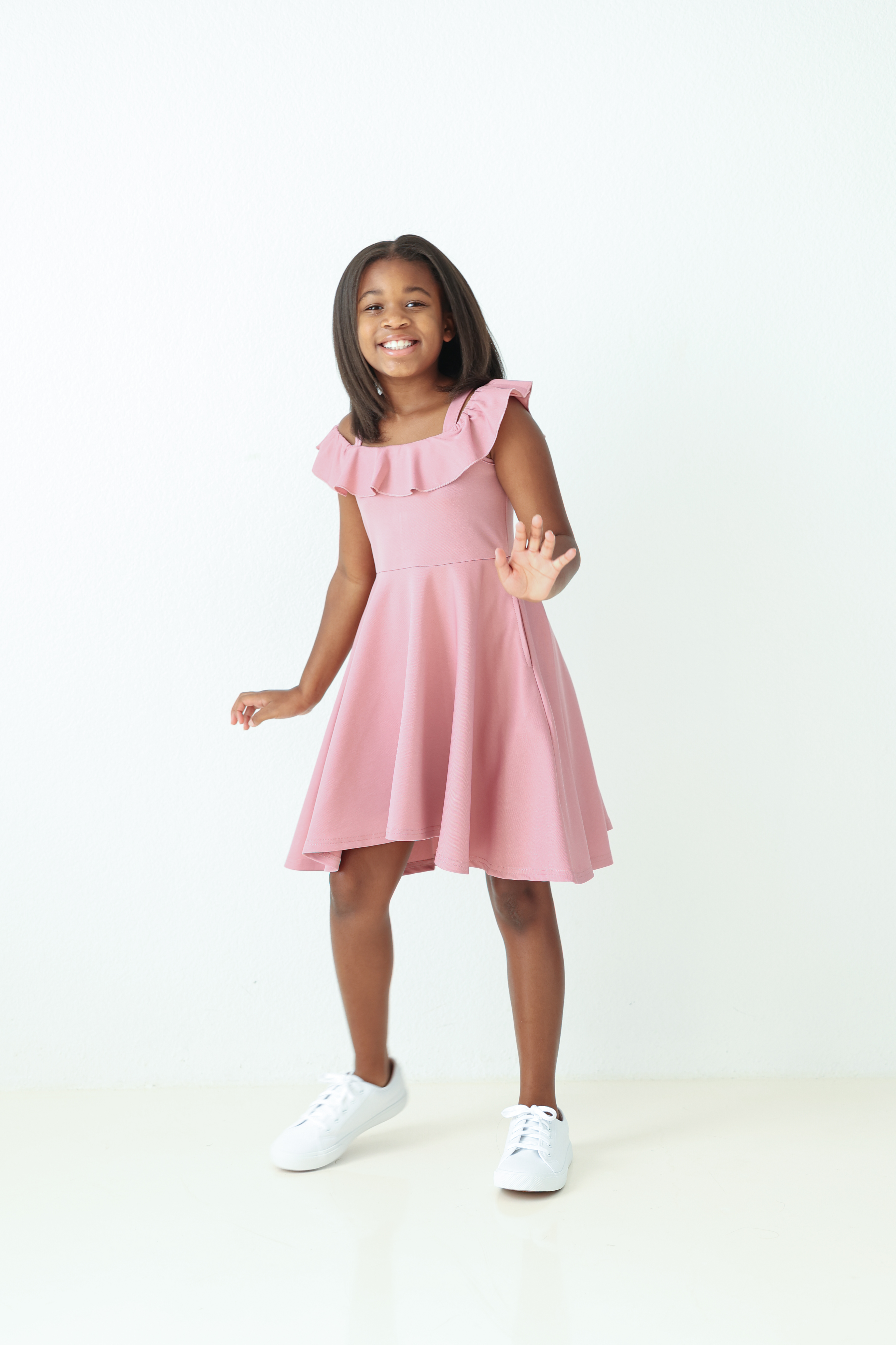 Kennedy smiling in a pink dress and white sneakers